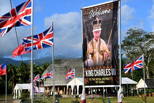 Niños juegan rugby cerca de una valla con la imagen del rey Carlos III en la aldea de Siumu, en Samoa, el 22 de octubre de 2024