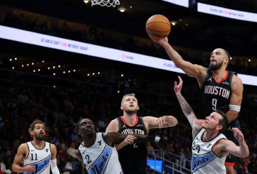 El jugador de los Houston Rockets Dillon Brooks toca una pelota rebotada saltando sobre Garrison Mathews, de los Hawks, en el tercer cuarto de su partido de la NBA, el 28 de enero de 2025 en Atlanta, Georgia (EEUU)