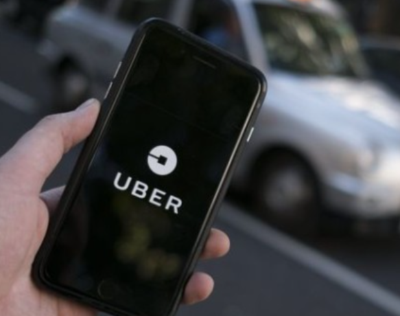 AFP | Una persona sostiene un celular para acceder a Uber.