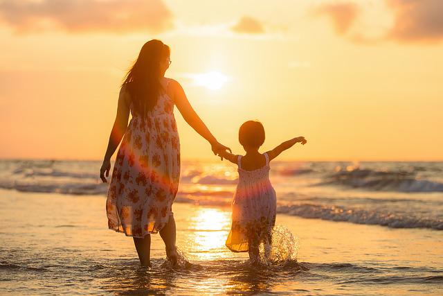 PIXABAY | Una madre agarrada de la mano con su hija en una playa viendo el atardecer.