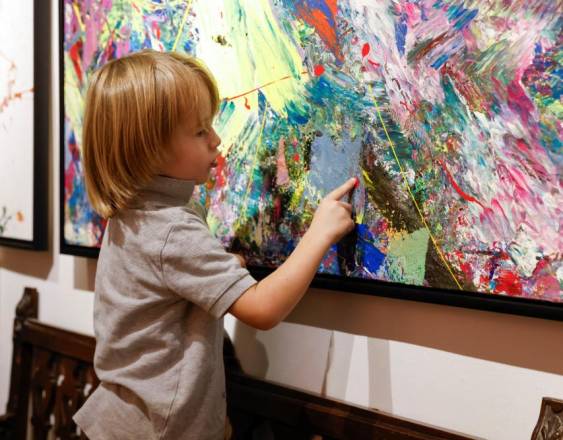 Laurent Schwarz, three years old, explains one of his artworks in his parents' house in Neubeuern near Rosenheim, southern Germany on October 17, 2024. - He still wears diapers, but in just a few months he has become an Instagram and art world star. Some media outlets have already dubbed him the Mini-Picasso. In his studio, the three-year-old German toddler paints canvases that are often larger than he is, with abstract and colorful patterns using brushes, rollers, or sometimes simply with his fingers covered in paint. He discovered this passion almost a year ago, during a vacation in a family hotel that had a studio. (Photo by Michaela STACHE / AFP)