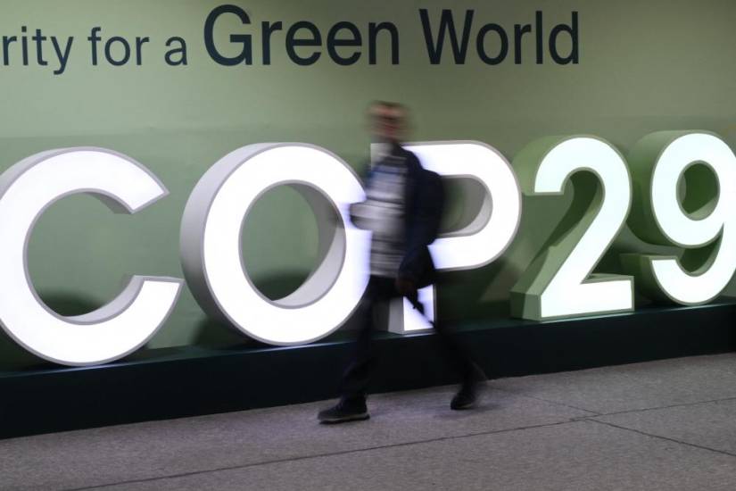 AFP | Los asistentes pasan junto al logotipo de la COP29 durante la Conferencia de las Naciones Unidas sobre el Cambio Climático.