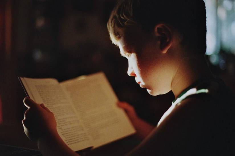 Pixabay | Un niño sostiene un libro abierto.