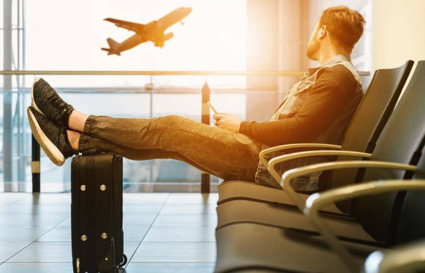 Pexels | Una persona en el aeropuerto viendo despegar un avión bajo la puesta del sol.