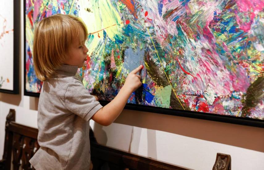 Laurent Schwarz, three years old, explains one of his artworks in his parents' house in Neubeuern near Rosenheim, southern Germany on October 17, 2024. - He still wears diapers, but in just a few months he has become an Instagram and art world star. Some media outlets have already dubbed him the Mini-Picasso. In his studio, the three-year-old German toddler paints canvases that are often larger than he is, with abstract and colorful patterns using brushes, rollers, or sometimes simply with his fingers covered in paint. He discovered this passion almost a year ago, during a vacation in a family hotel that had a studio. (Photo by Michaela STACHE / AFP)