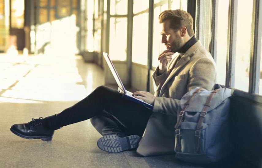 Un hombre con una laptop conectándose a una red WiFi.